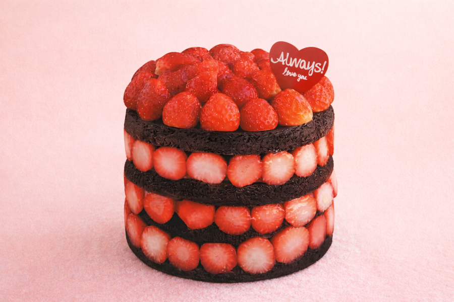 A photo-style image of a tall layered strawberry cake with dark chocolate sponge and fresh strawberries neatly stacked between each layer, topped with whole strawberries on a soft pastel background.