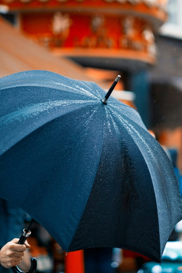 A person holding an umbrella in the rain, symbolizing leadership providing protection and stability when employees feel uncertain about job security.