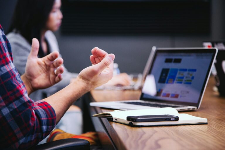 Employee gesturing while speaking during a workplace meeting, representing communication, affirmation, and engagement at work.