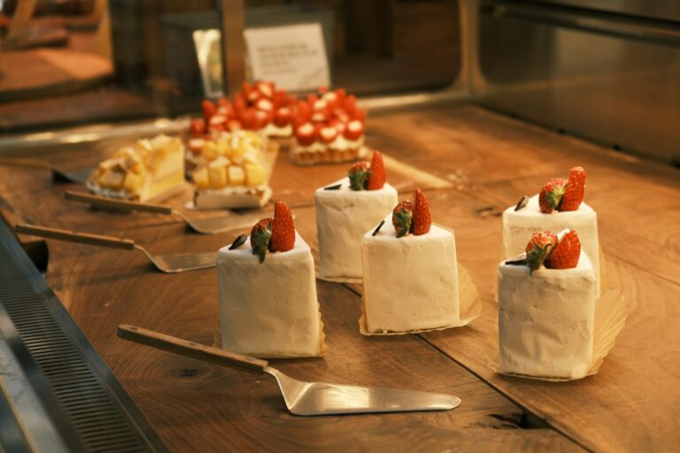 Korean-style strawberry cream cakes arranged on a wooden bakery display, showcasing premium desserts with fresh fruit toppings.