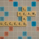 Scrabble board spelling ‘TEAM’, ‘LEAD’, and ‘SUCCEED’, symbolizing teamwork, leadership, and successful strategy execution.