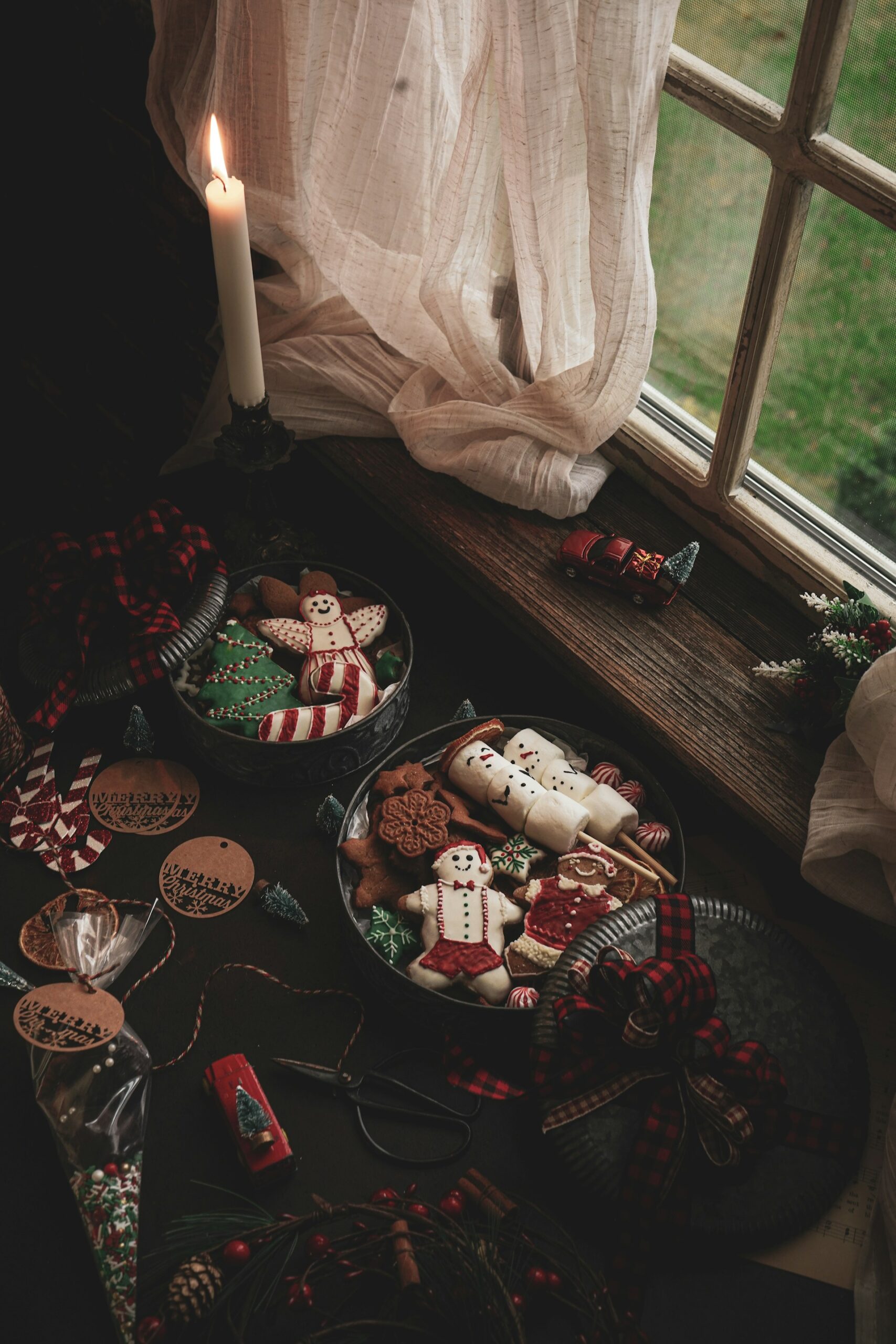 A cozy Christmas Eve scene with homemade gingerbread cookies, festive treats, and a lit candle by a window, creating a warm holiday atmosphere of reflection and comfort.